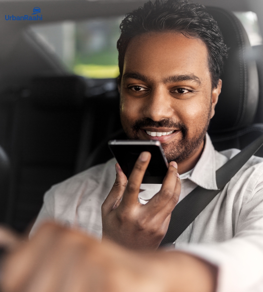 Man smiling while using phone inside an UrbanRaahi rental car